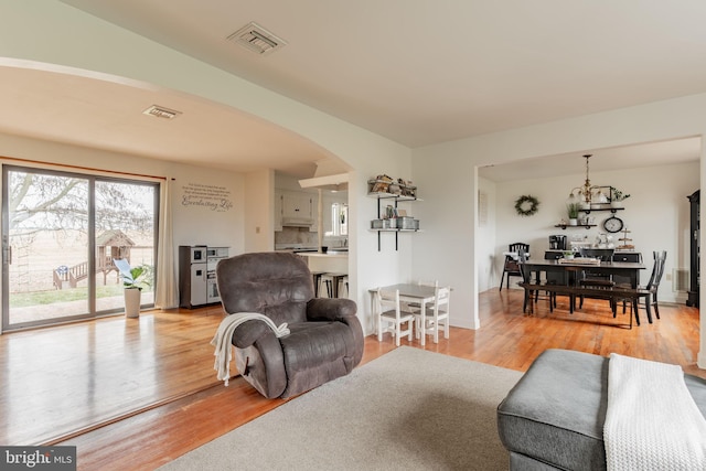 living room featuring arched walkways, visible vents, and light wood-type flooring