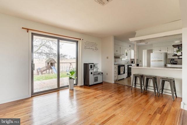 living area with light wood-style floors, visible vents, and baseboards