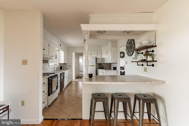 kitchen with decorative backsplash, white appliances, white cabinetry, and a peninsula