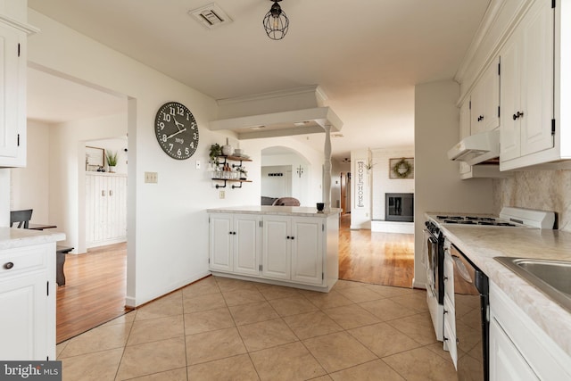 kitchen with under cabinet range hood, light tile patterned floors, dishwasher, and white gas range