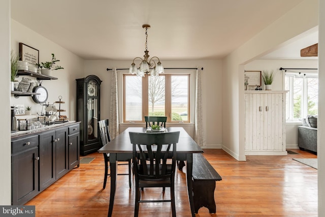 dining room featuring baseboards, light wood-type flooring, and a chandelier