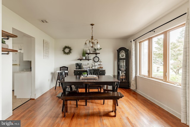 dining room featuring visible vents, baseboards, light wood-style flooring, and a chandelier