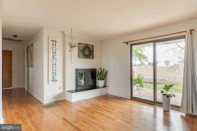 unfurnished living room with visible vents, baseboards, a fireplace, and light wood finished floors