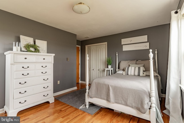 bedroom featuring light wood-style floors, baseboards, and a closet