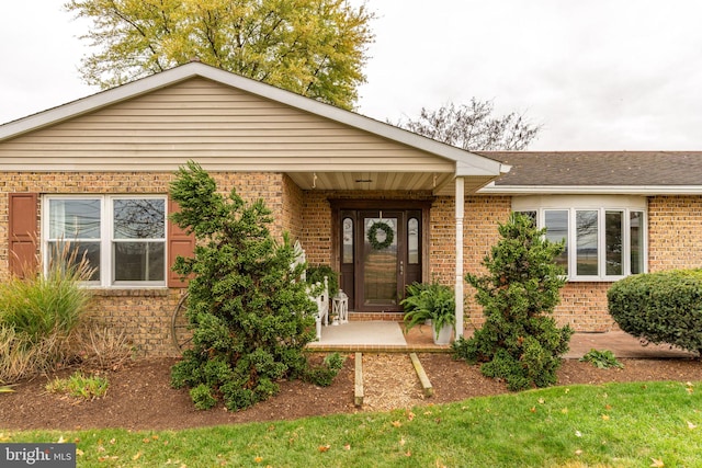 property entrance with brick siding and a shingled roof