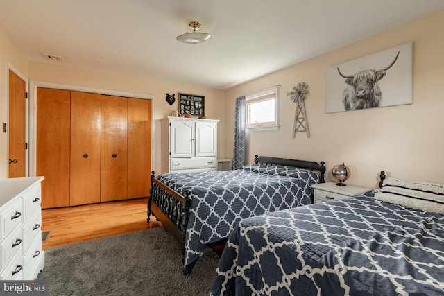 bedroom with a closet, visible vents, and light wood finished floors