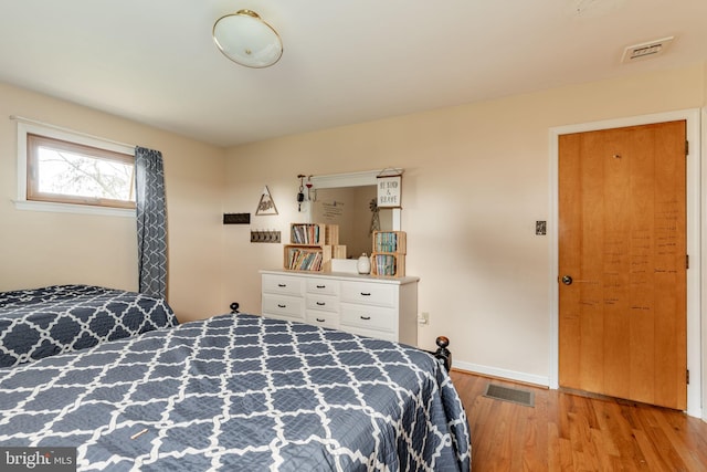 bedroom with visible vents, baseboards, and wood finished floors