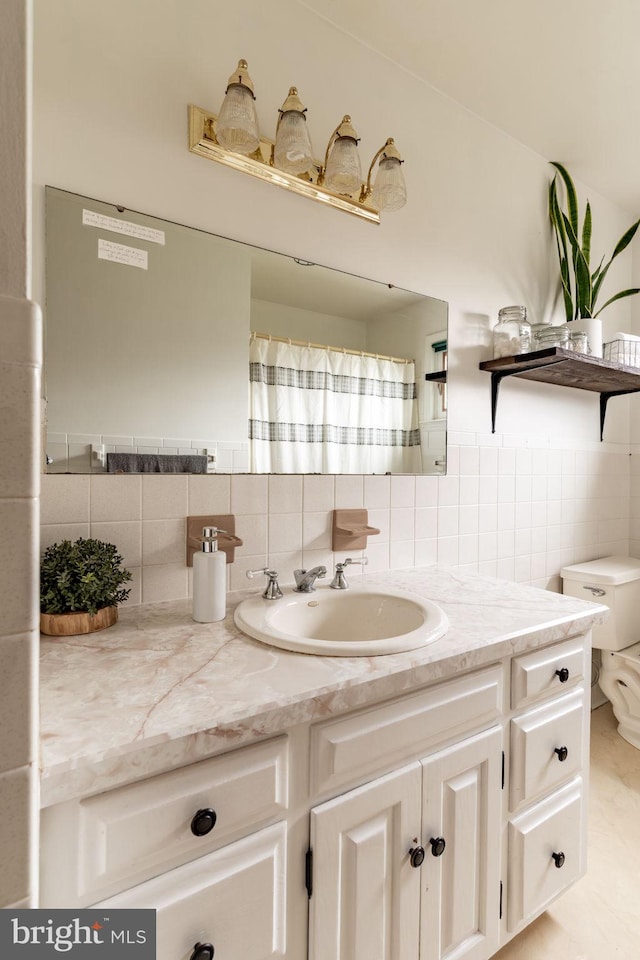 bathroom featuring toilet, vanity, and tile walls