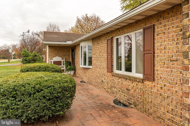 view of property exterior with brick siding and a patio area