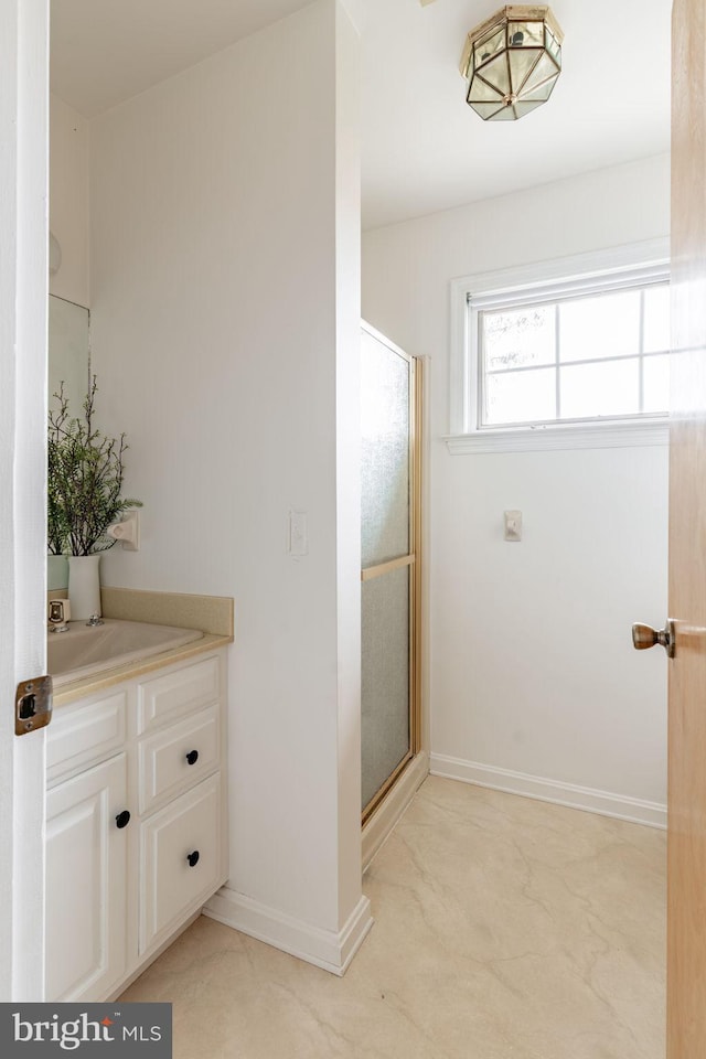 full bath with baseboards, vanity, and a shower stall