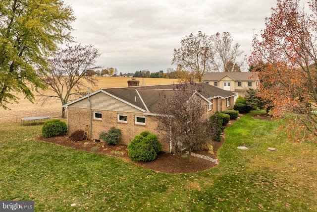 view of property exterior with brick siding, a lawn, and a trampoline