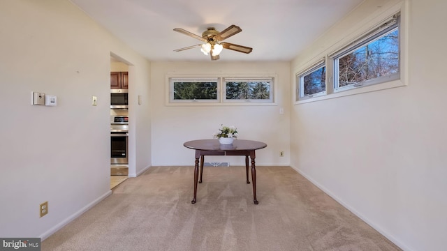 dining room featuring a ceiling fan, baseboards, and light carpet