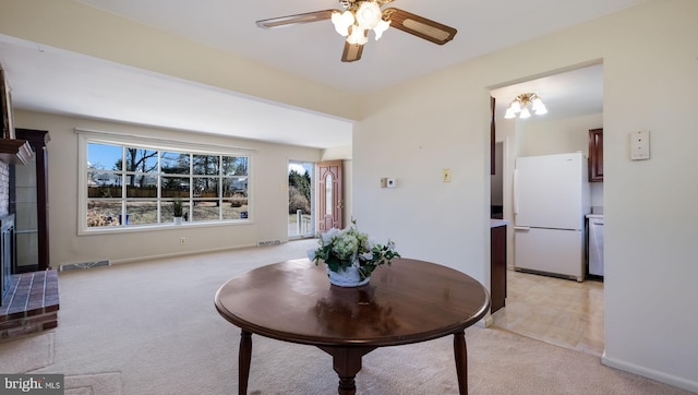 dining room featuring visible vents, light carpet, baseboards, and a ceiling fan