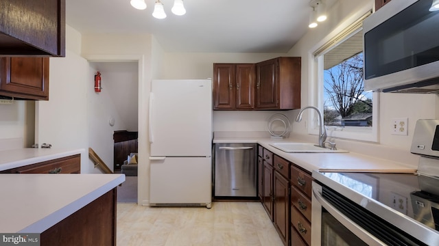 kitchen with a sink, stainless steel appliances, dark brown cabinetry, and light countertops