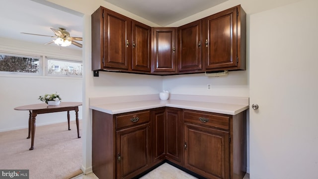 kitchen with light colored carpet, dark brown cabinets, ceiling fan, and light countertops