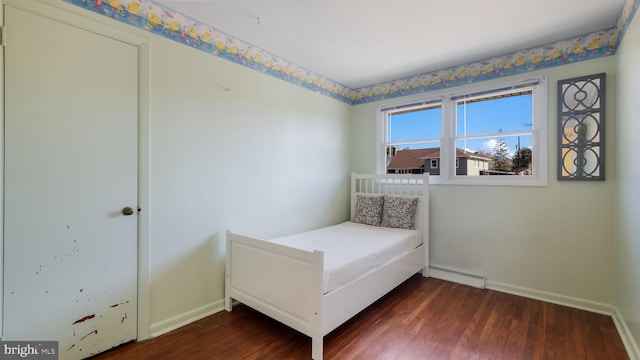 bedroom featuring a baseboard radiator, baseboards, and dark wood-style flooring