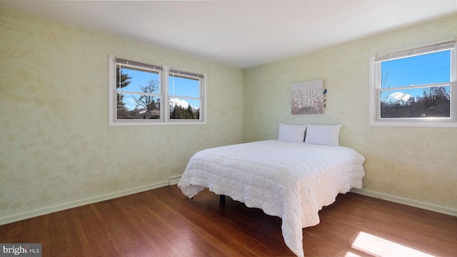 bedroom featuring baseboards, multiple windows, and wood finished floors