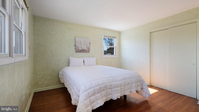 bedroom with a closet, baseboards, and wood finished floors