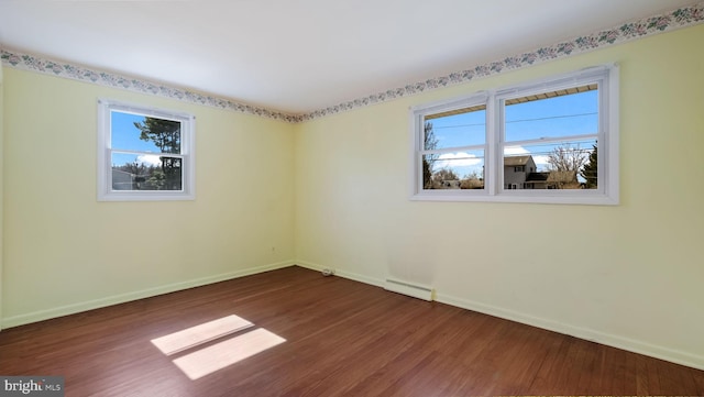 unfurnished room with dark wood finished floors, plenty of natural light, and baseboards