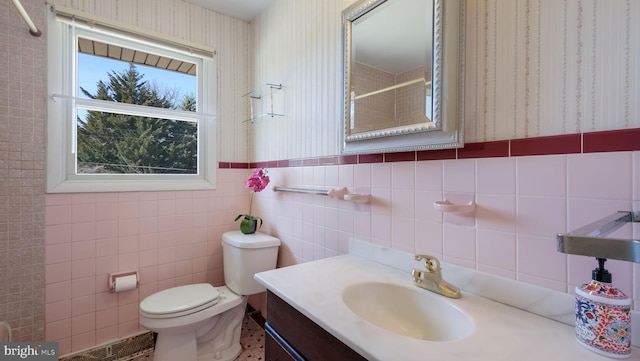 bathroom with a shower, toilet, tile walls, and wallpapered walls