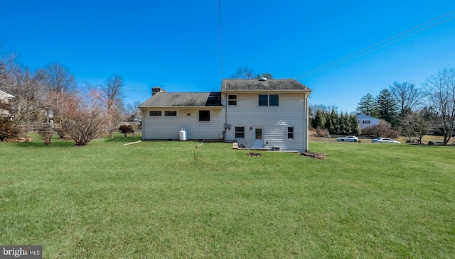 back of property with a lawn and a chimney