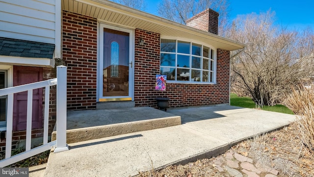 entrance to property featuring brick siding and a chimney