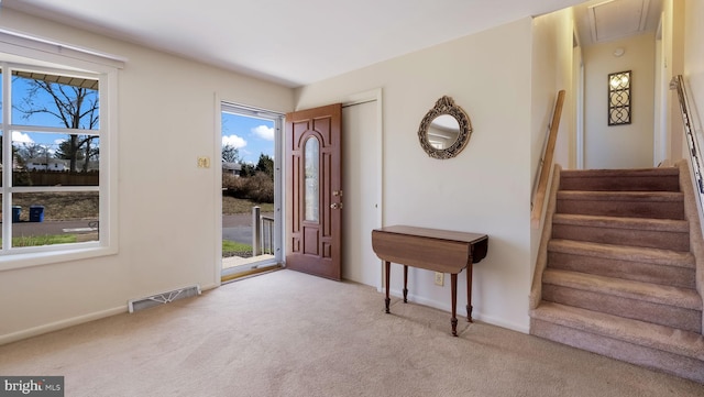 entrance foyer with visible vents, stairway, baseboards, and carpet