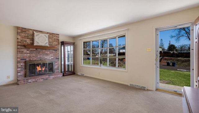 unfurnished living room featuring a brick fireplace, carpet flooring, baseboards, and visible vents