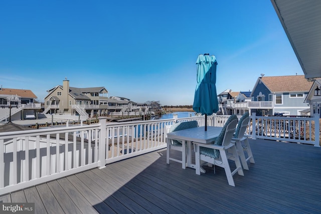 deck featuring a residential view, outdoor dining area, and a water view