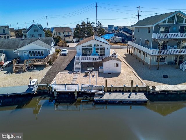 exterior space featuring a deck with water view, a fenced backyard, dirt driveway, and stairway