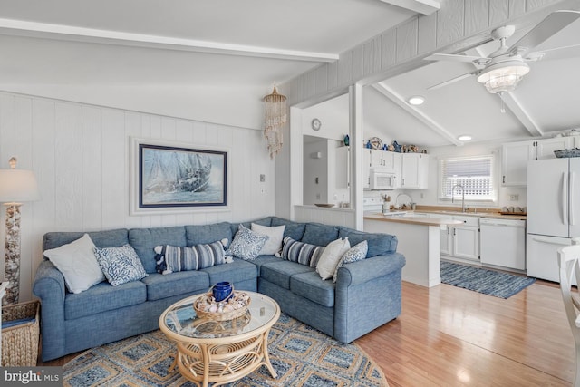 living area featuring light wood-style flooring, lofted ceiling with beams, and a ceiling fan