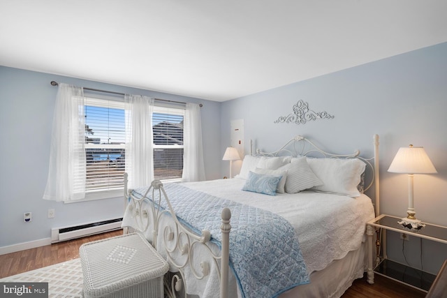 bedroom with a baseboard heating unit, baseboards, and wood finished floors