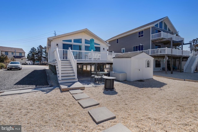 rear view of property with a storage shed, stairway, an outbuilding, and a patio area