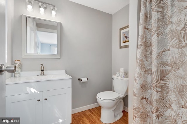 bathroom featuring toilet, vanity, baseboards, and wood finished floors