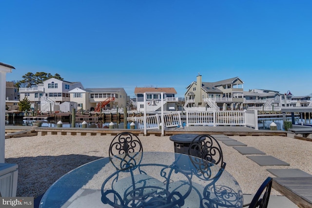 view of patio with outdoor dining area, a residential view, a dock, and a water view