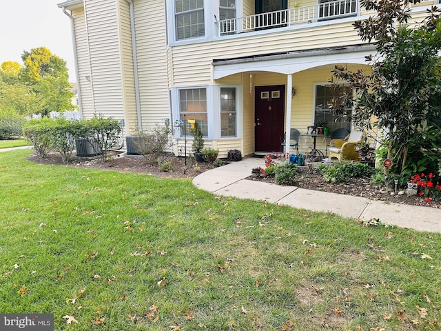 property entrance with a lawn and a balcony