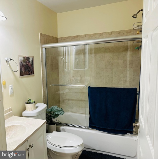 bathroom with combined bath / shower with glass door, toilet, and vanity