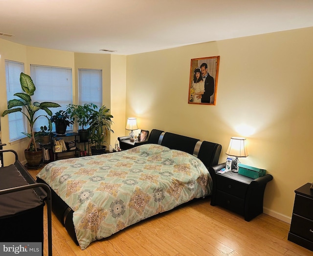 bedroom featuring wood finished floors, visible vents, and baseboards