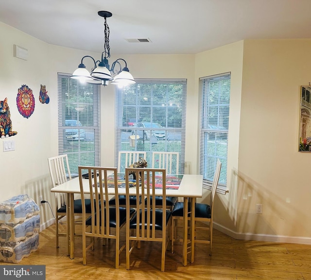 dining area featuring baseboards, wood finished floors, visible vents, and a chandelier