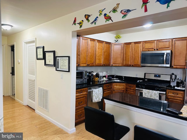 kitchen featuring brown cabinetry, visible vents, appliances with stainless steel finishes, and light wood-style floors