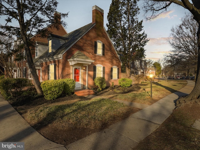 view of front of home featuring brick siding and a chimney