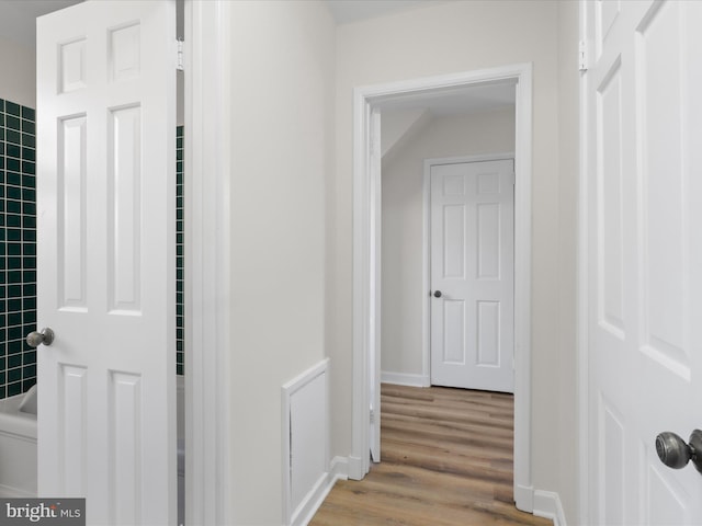 corridor featuring baseboards and wood finished floors