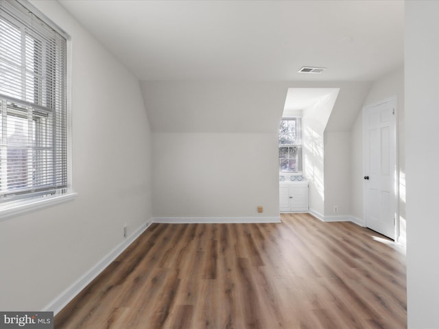 bonus room featuring lofted ceiling, wood finished floors, baseboards, and visible vents