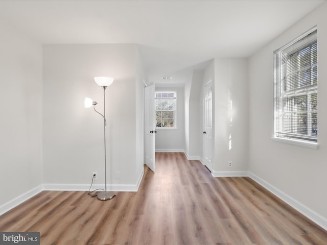 spare room featuring baseboards and light wood-style floors