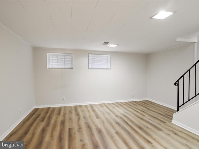 below grade area with stairs, baseboards, and light wood finished floors