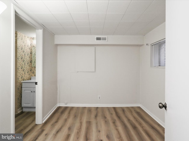 basement featuring visible vents, baseboards, and wood finished floors