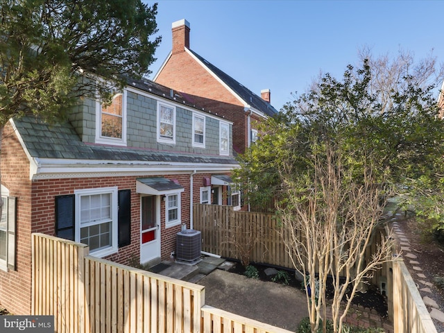 back of property featuring central air condition unit, fence, and brick siding