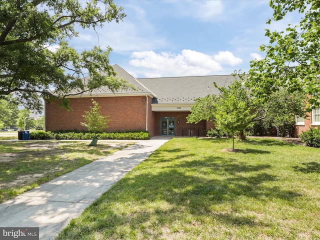 view of front facade with brick siding, french doors, and a front lawn