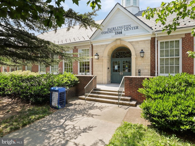 view of exterior entry featuring french doors and brick siding