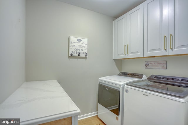 laundry room featuring washer and dryer, light wood-style floors, cabinet space, and baseboards